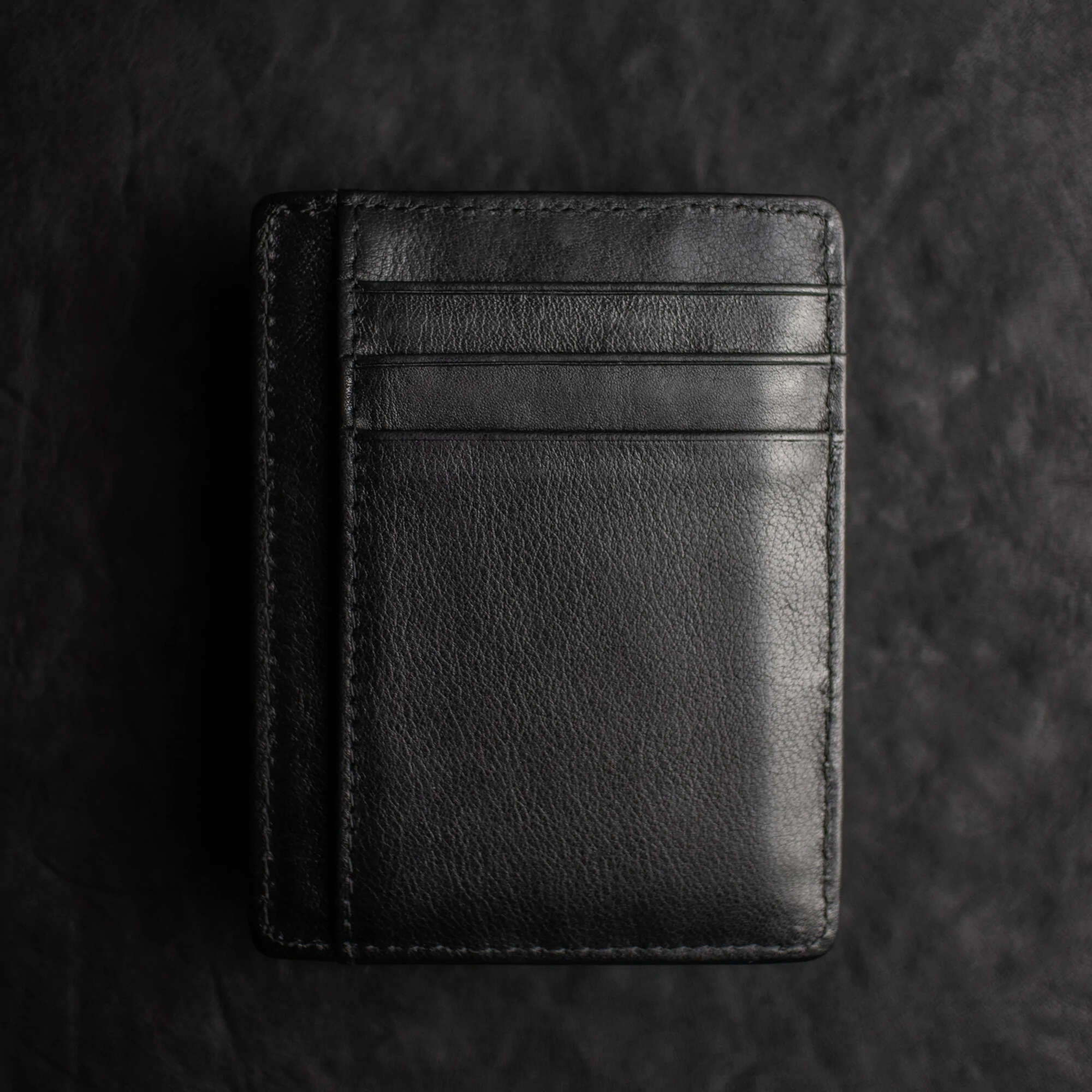 Black Shadow Wallet by Dee Christopher on black surface (back view)