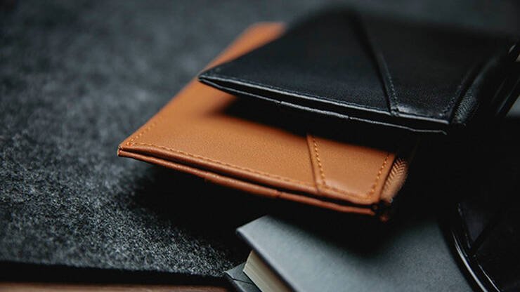 The edge wallet by TCC  brown a black leaning against a book different angle