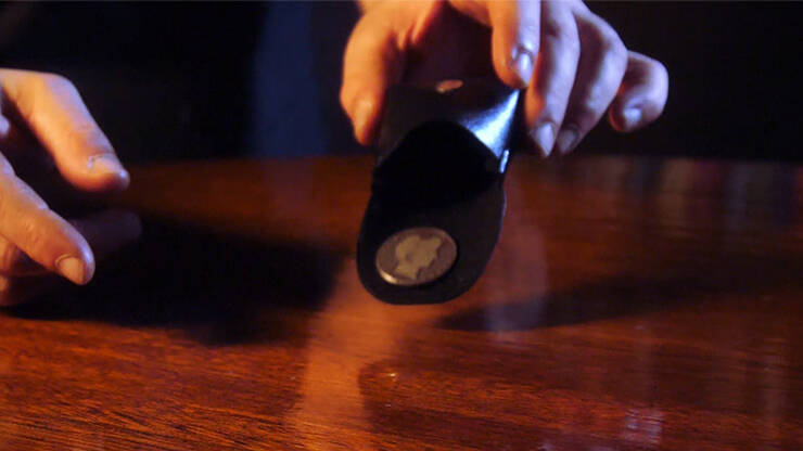 The Fooler Wallet by Eric Roumestan with coin sliding out onto wooden surface