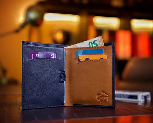 The Rebel Elite Wallet by Secret Tannery tanding on edge on wooden surface with money and cards inside