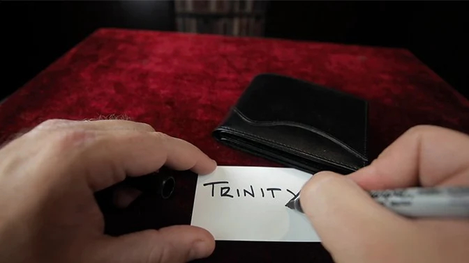 Trinity Wallet by Matthew Wright shown closed and someone writing "trinity" on a business card with a sharpie